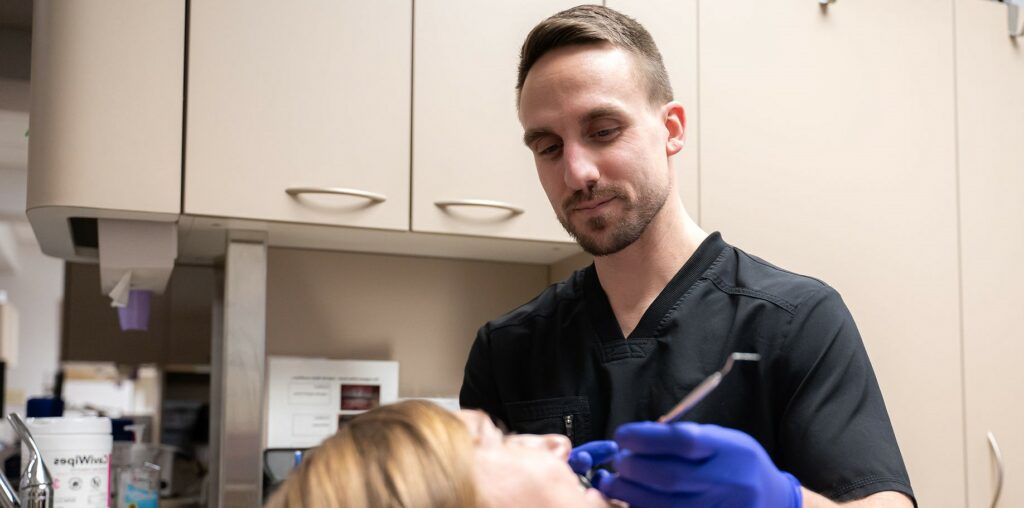 Dental professional examining a patient’s teeth in a clinic setting.