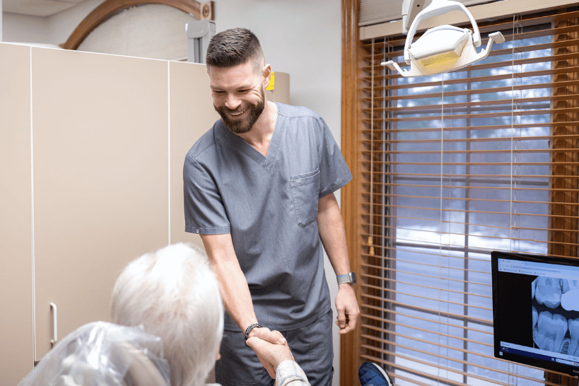 Dentist at Kondas Dental Group shaking hands with patient after dental implant consultation